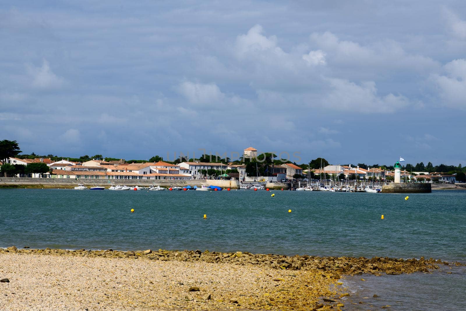 View on the Phare de la Flotte and some boats on the sea from the beach plage de l' Arnérault on a sunny summerday with the city in the background