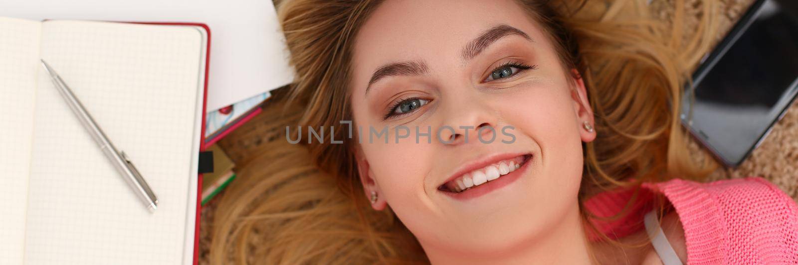 Portrait of beautiful woman lies on floor with diary. Learning and education concept