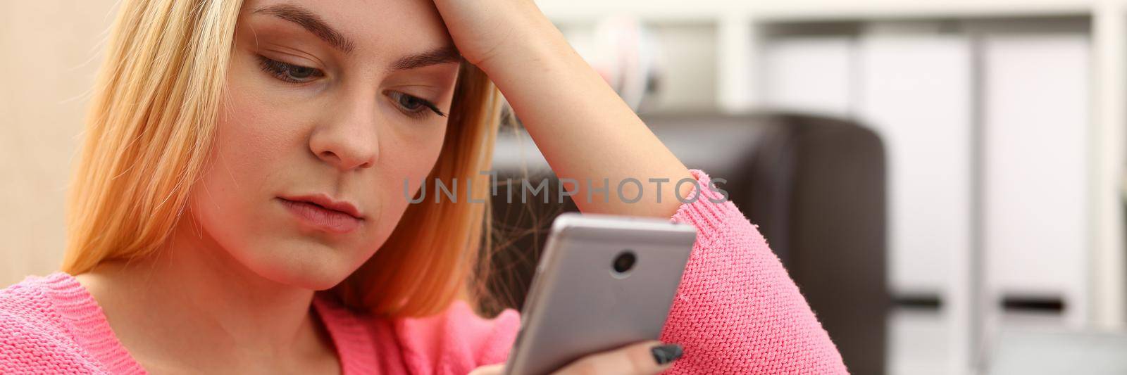 Sad woman looks at smartphone screen closeup by kuprevich