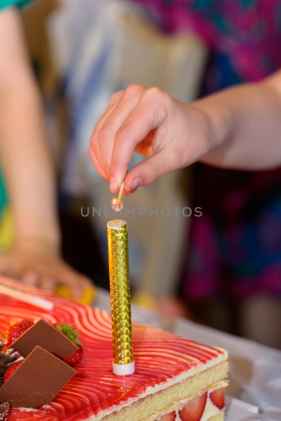 closeup of a womans hand starting with a match  a fountain firework on a cake