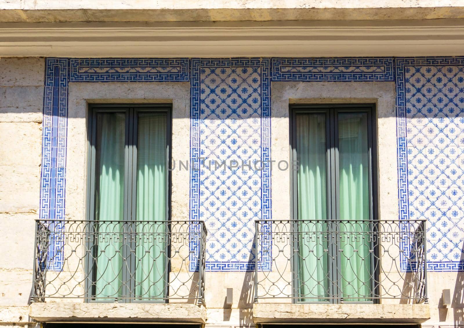 Beige facade of an old Portuguese house covered with blue azulejo tiles with windows and balconies