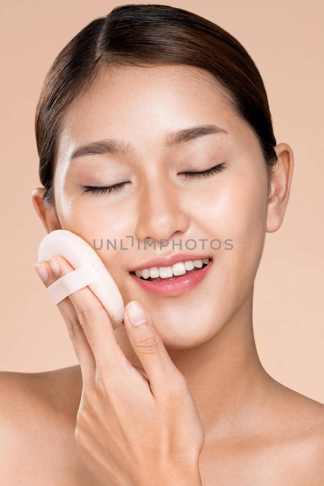 Closeup ardent woman applying her cheek with dry powder and looking at camera. Portrait of younger with perfect makeup and healthy skin concept.