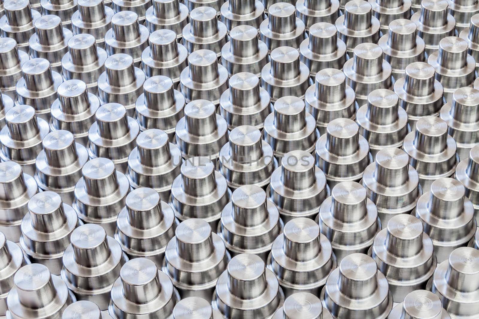 Many turning shiny steel parts laid tightly on a flat surface - full frame batch processing manufacturing background,