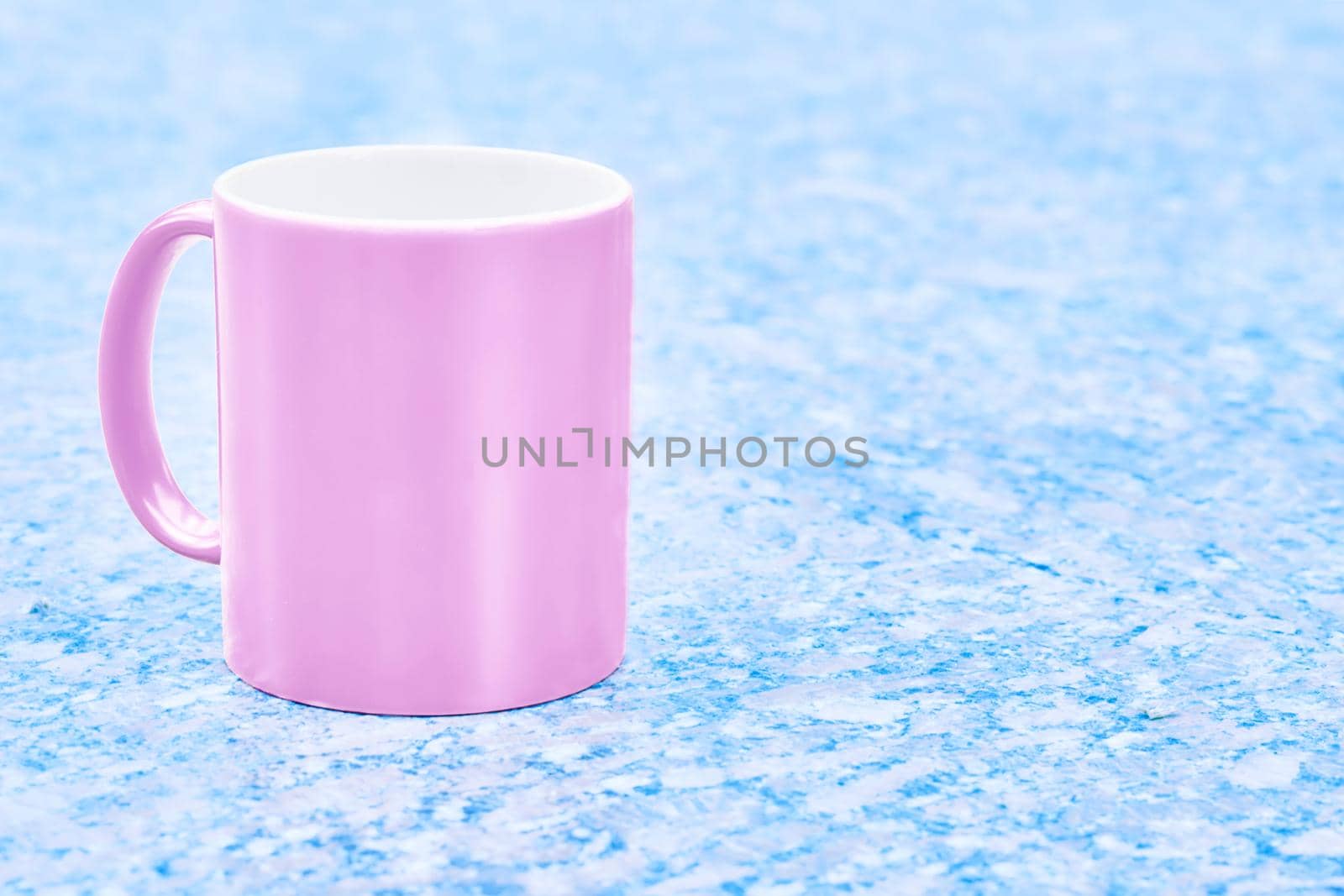 a small bowl-shaped container for drinking from, typically having a handle. Pink ceramic cup mug on blue ice frosty spotted surface