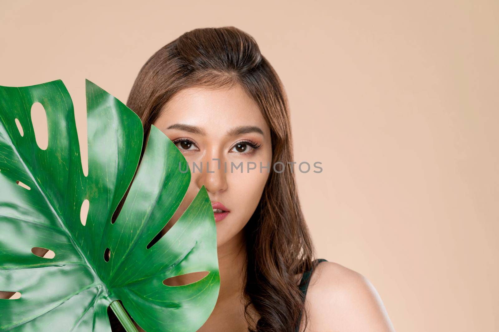 Closeup young ardent woman with healthy skin holding green leaf near her face. by biancoblue