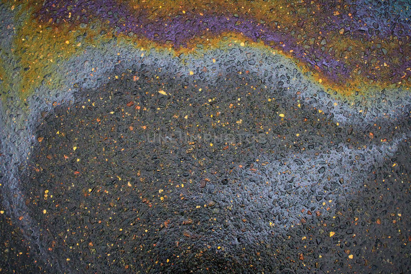 Rainbow gasoline oil spill on the pavement as a texture or background.