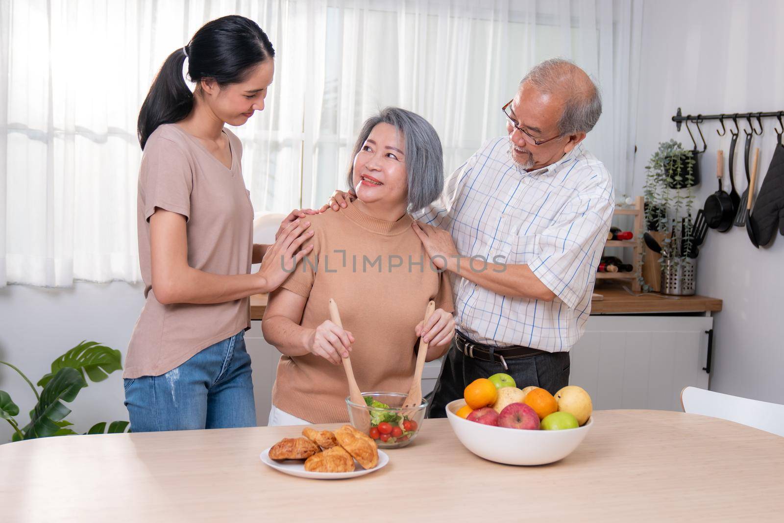 Contented family, daughter, father, mother prepare bread veggies and fruit salad together in their kitchen.