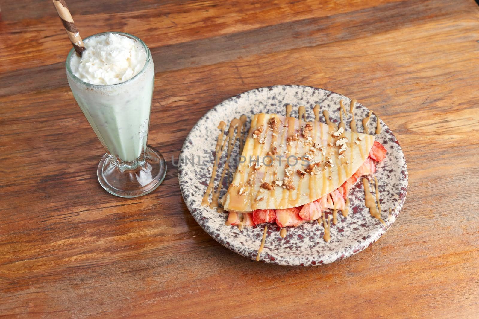 photo of delicious crepe with strawberry, walnut and decorated with cajeta, served with vanilla malteda sweet crepe.