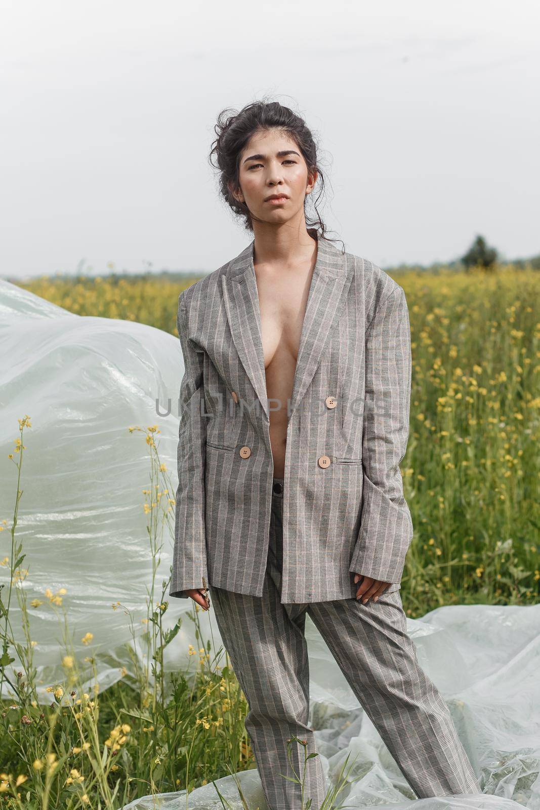 An Asian model poses in a field of yellow flowers for a clothing brand, polyethylene is the main props for a photo shoot. by Annu1tochka