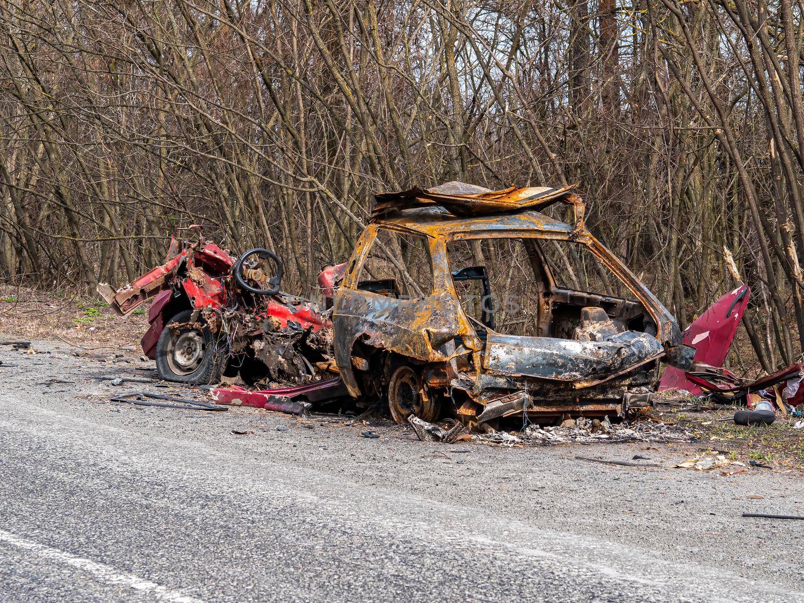 Road traffic accident of a car with fire. Car accident. Road in the forest. Damaged transport. Asphalt pavement. Traffic Laws. Military actions. Motor vehicle. Ukraine.