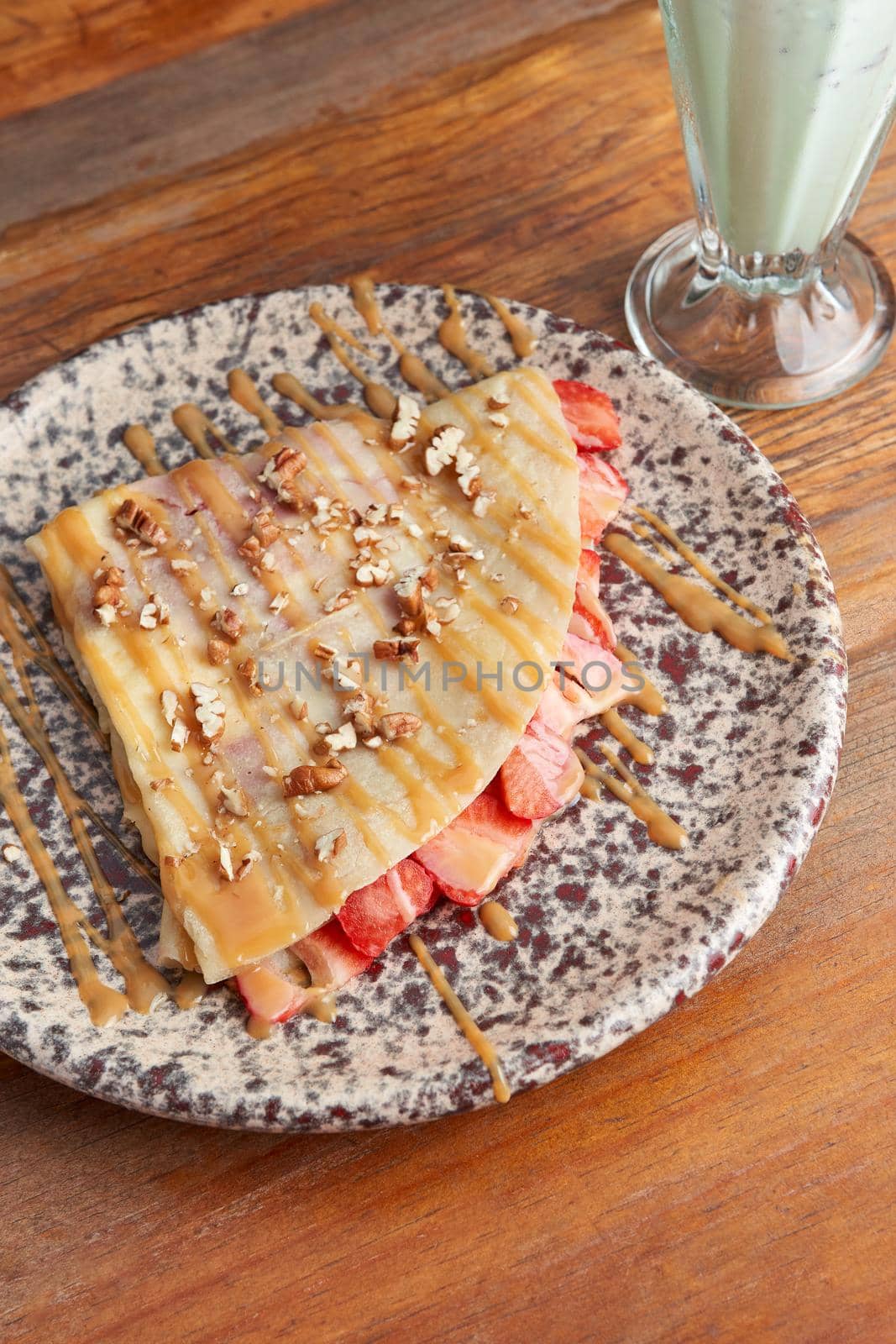 photo of delicious crepe with strawberry, walnut and decorated with cajeta, served with vanilla malteda sweet crepe.