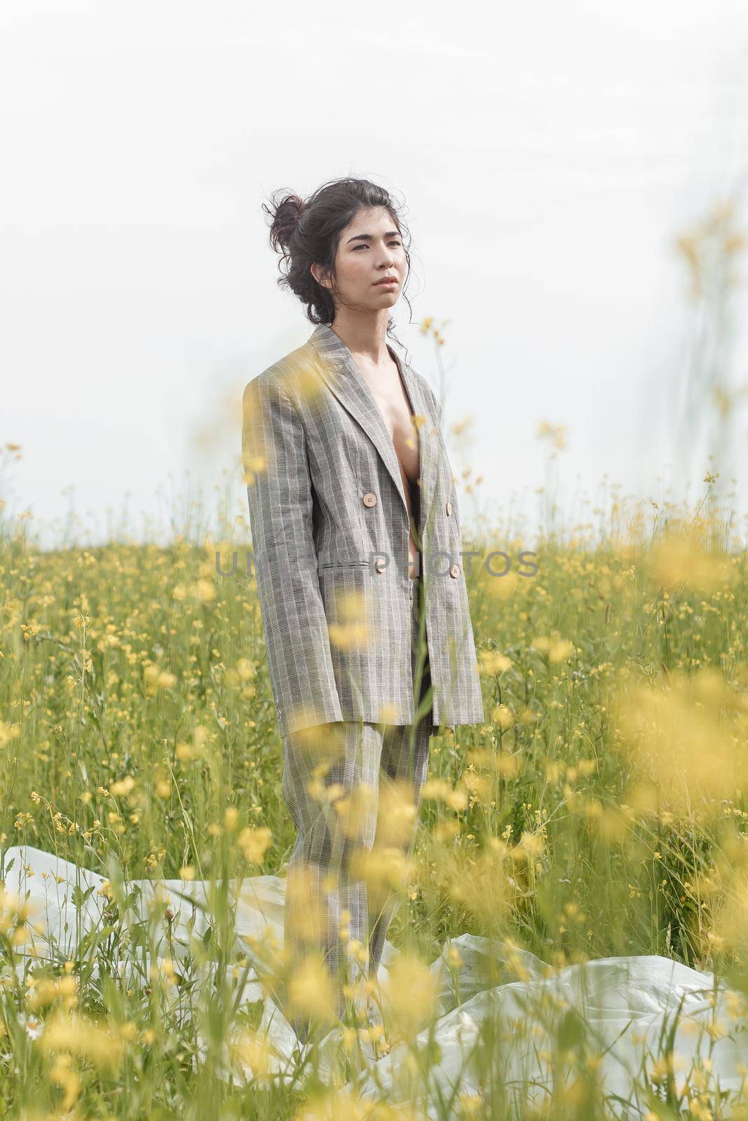 An Asian model poses in a field of yellow flowers for a clothing brand, polyethylene is the main props for a photo shoot. by Annu1tochka