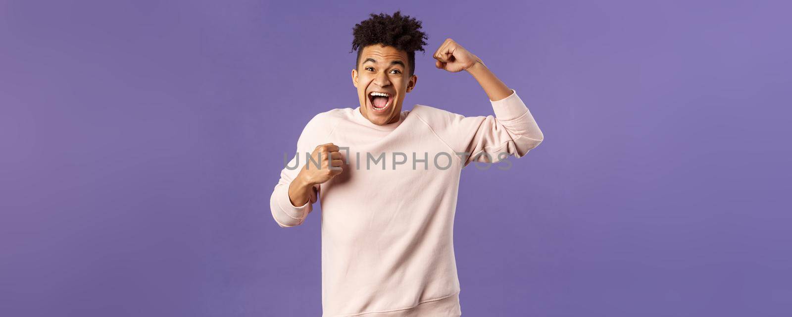 Portrait of excited happy man seeing his team scored goal on sports tv channel, chanting raise one hand in triumph, screaming in joy and happiness, celebrating victory, placed right bet.