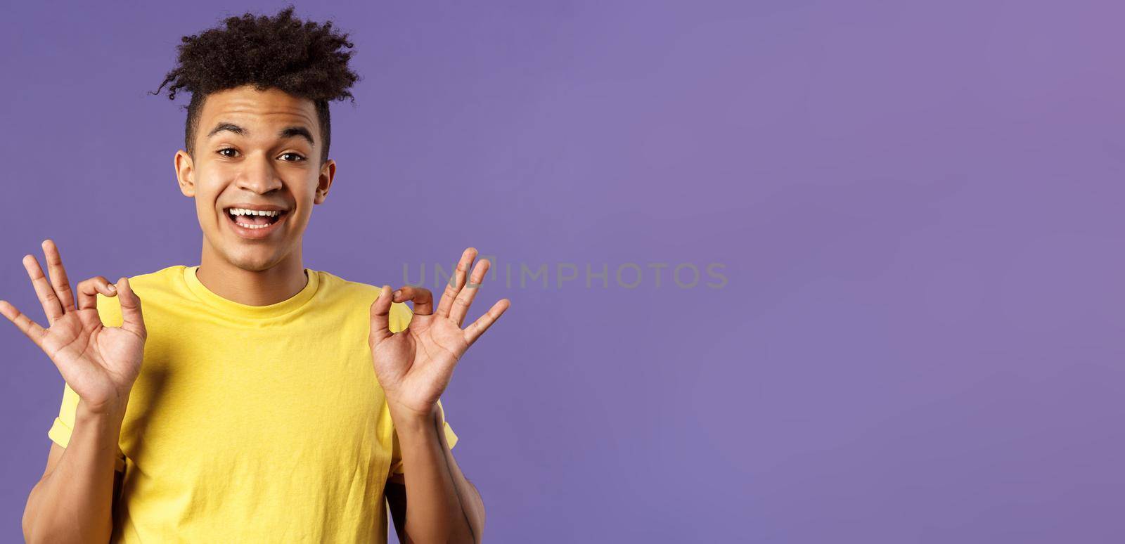 Close-up portrait of upbeat, relaxed young hipster guy with dreads assuring all good, everything be okay, show OK gesture and smiling, no problem guarantee best quality, purple background.