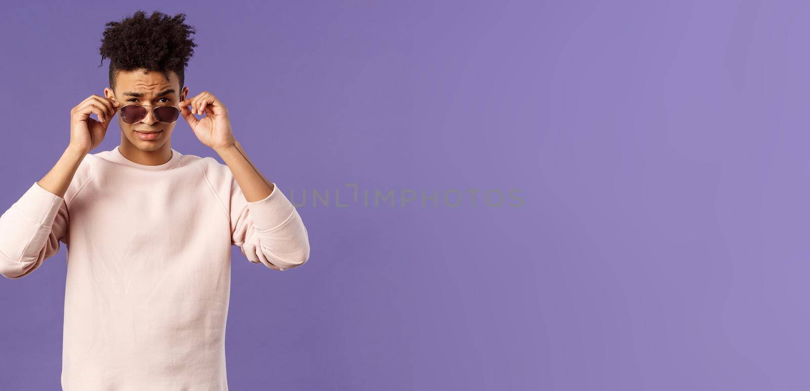 Portrait of sassy and confident young judgemental man, taking-off glasses squinting suspicious, security checking out and judging person near club door, standing purple background by Benzoix