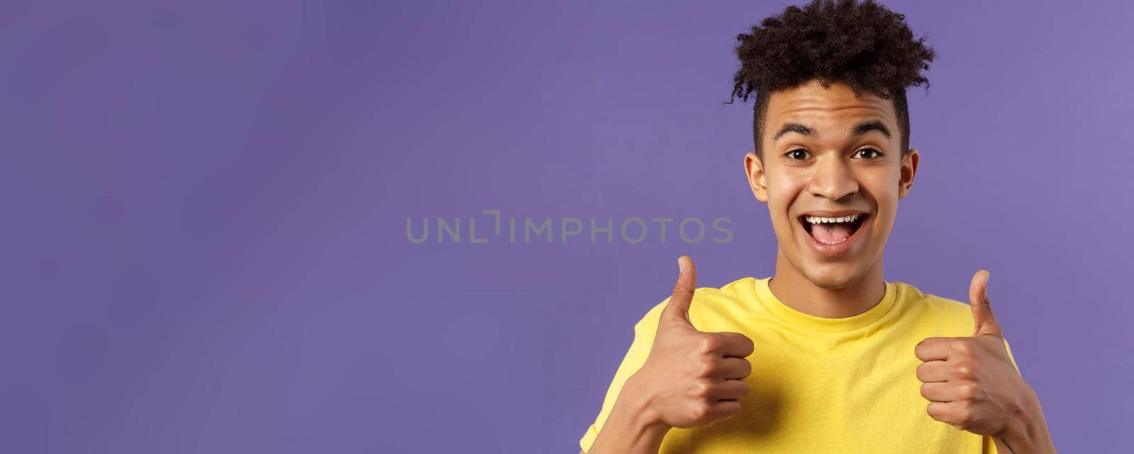 Close-up portrait of enthusiastic, lively hipster guy with afro haircut agree with something, show thumbs-up smiling with joy, recommend good product, like and approve plan, purple background by Benzoix