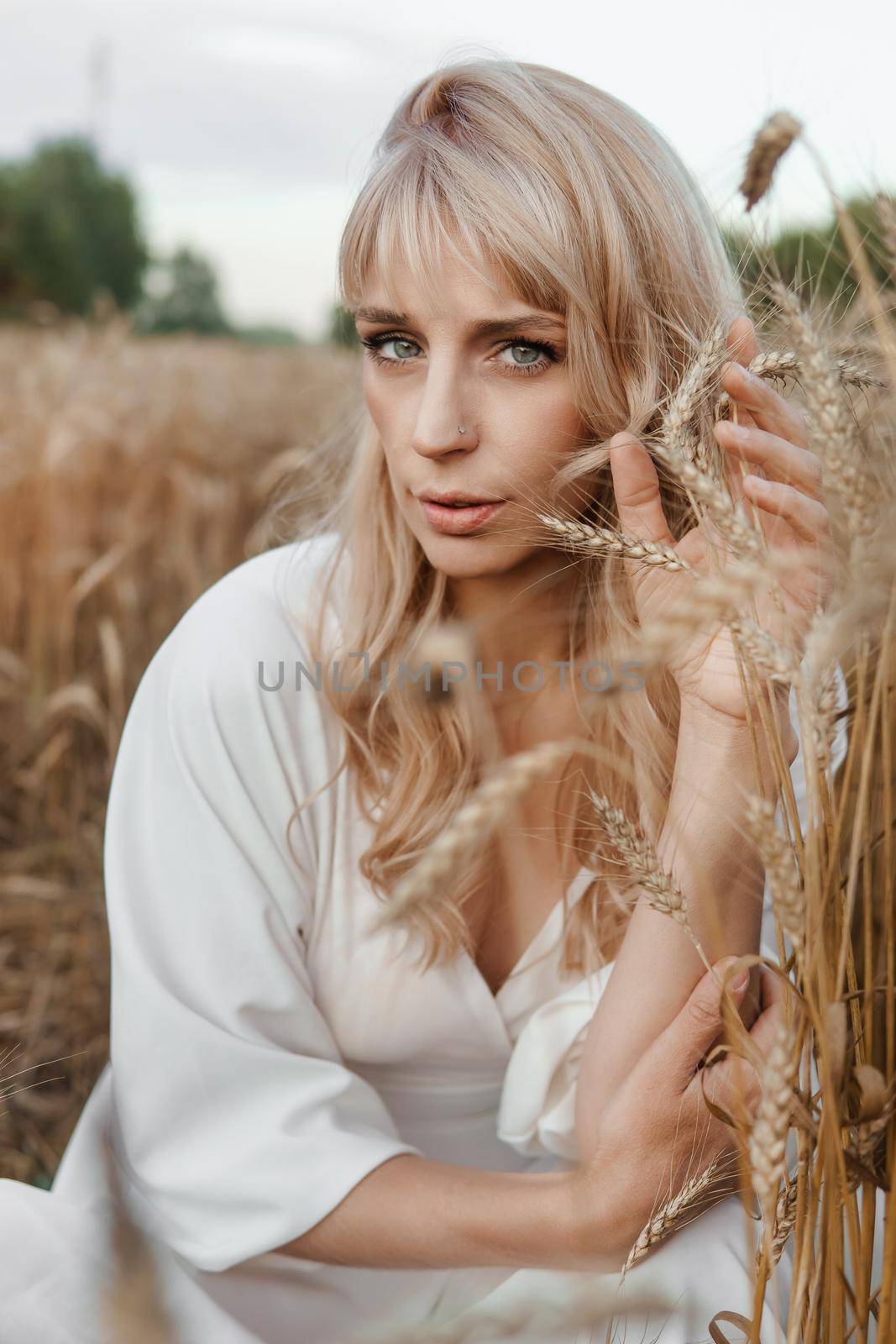 A blonde woman in a long white dress walks in a wheat field. The concept of a wedding and walking in nature by Annu1tochka