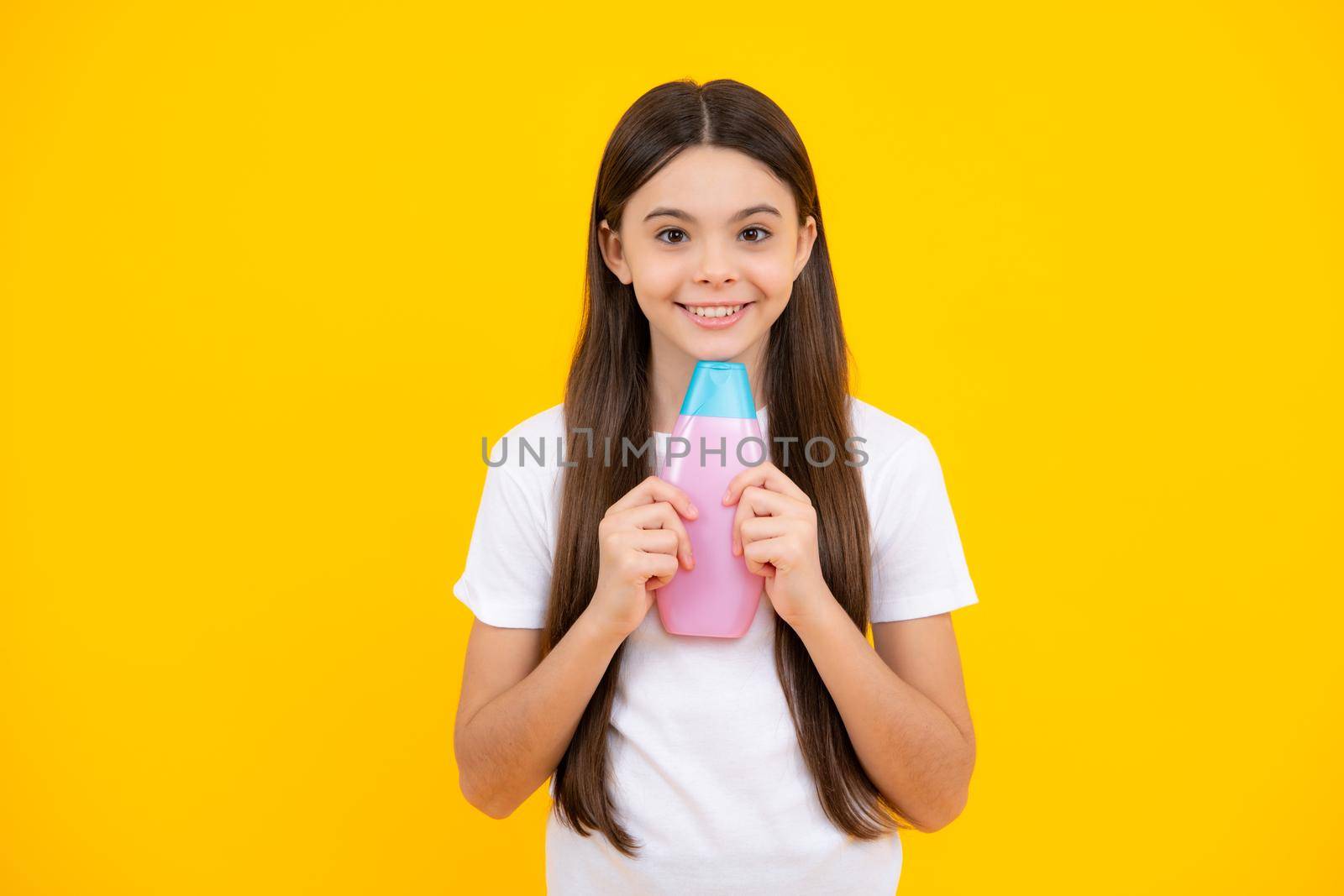 Child with shampoo conditioner. Daily cosmetic care. Teenager hold bottle of hair and skin care. Beauty health and cosmetics. Happy teenager portrait. Smiling girl. by RedFoxStudio