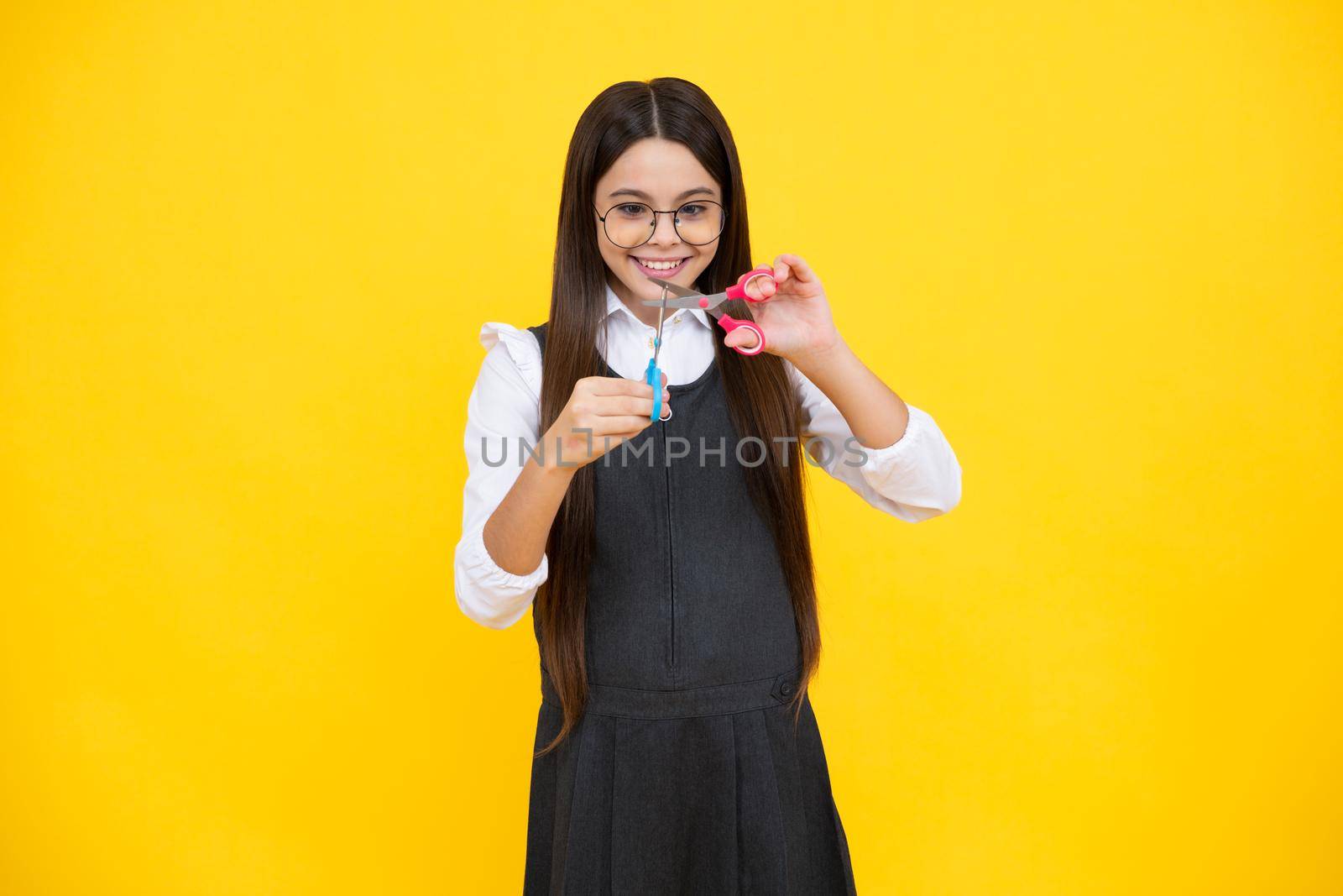 Teenage girl with scissors, isolated on yellow background. Child creativity, arts and crafts. by RedFoxStudio