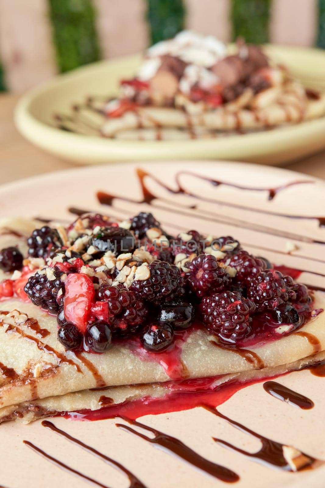 photo of delicious crepe with red berries, blackberries, blueberries, blueberries, strawberries and chocolate decoration. sweet crepe.