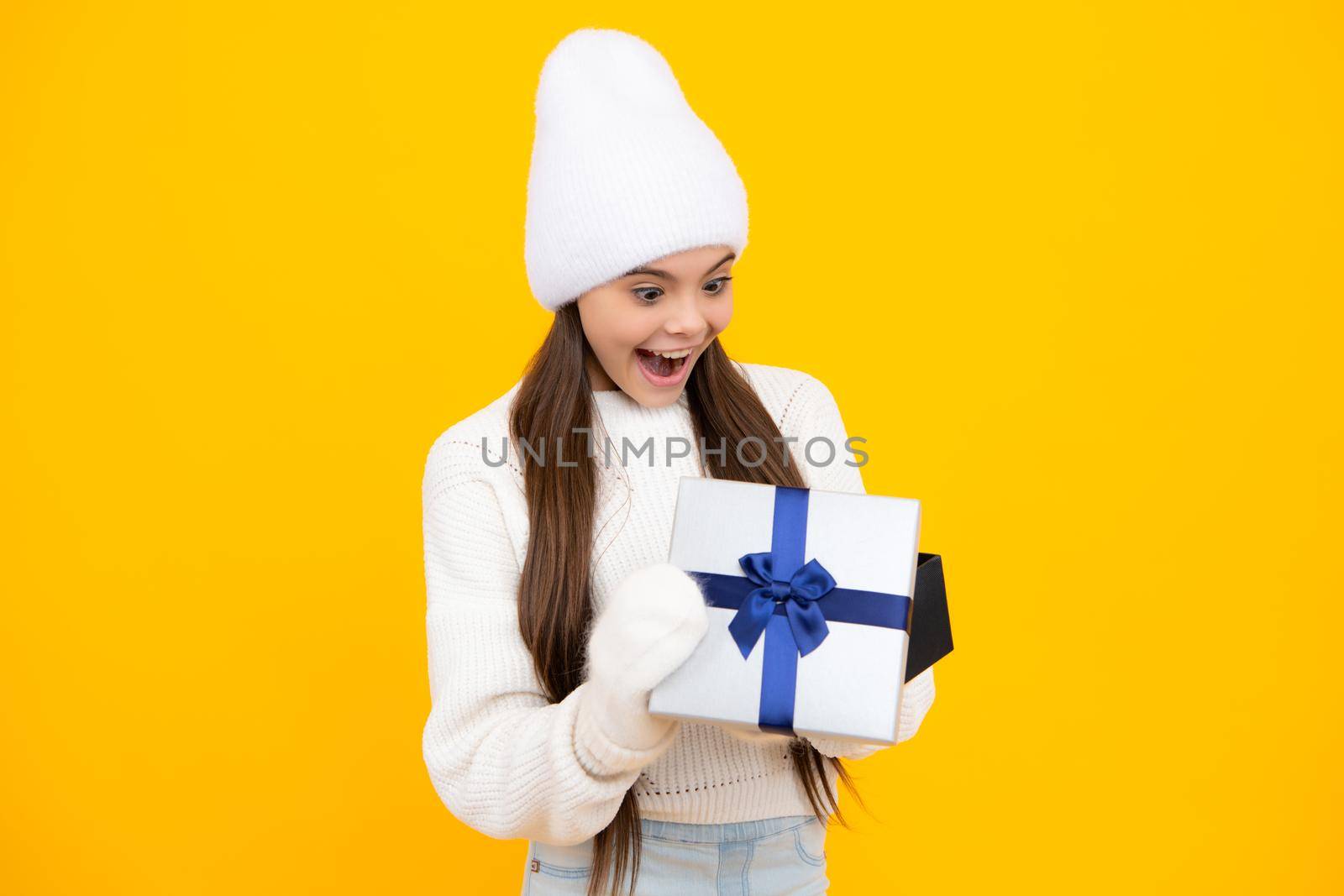Portrait of teenager child girl 12, 13, 14, years old holding Christmas gift box. Child in winter wear holding gift for New Year or Christmas