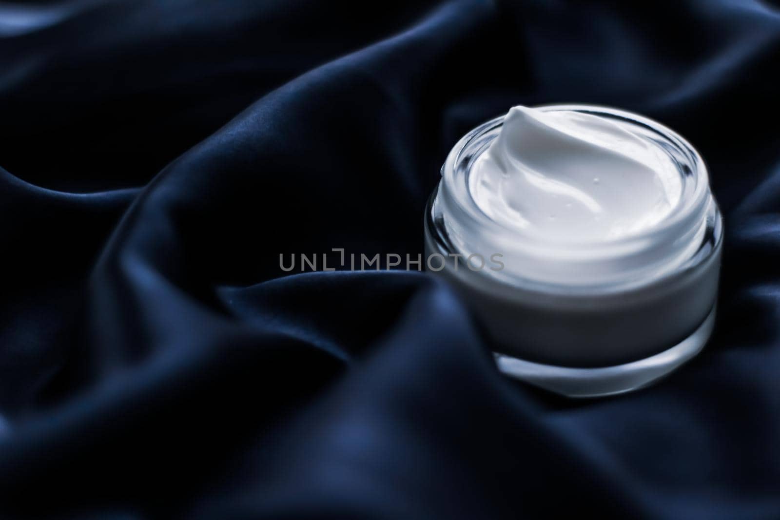 Luxury face cream jar on a dark blue silk by Anneleven