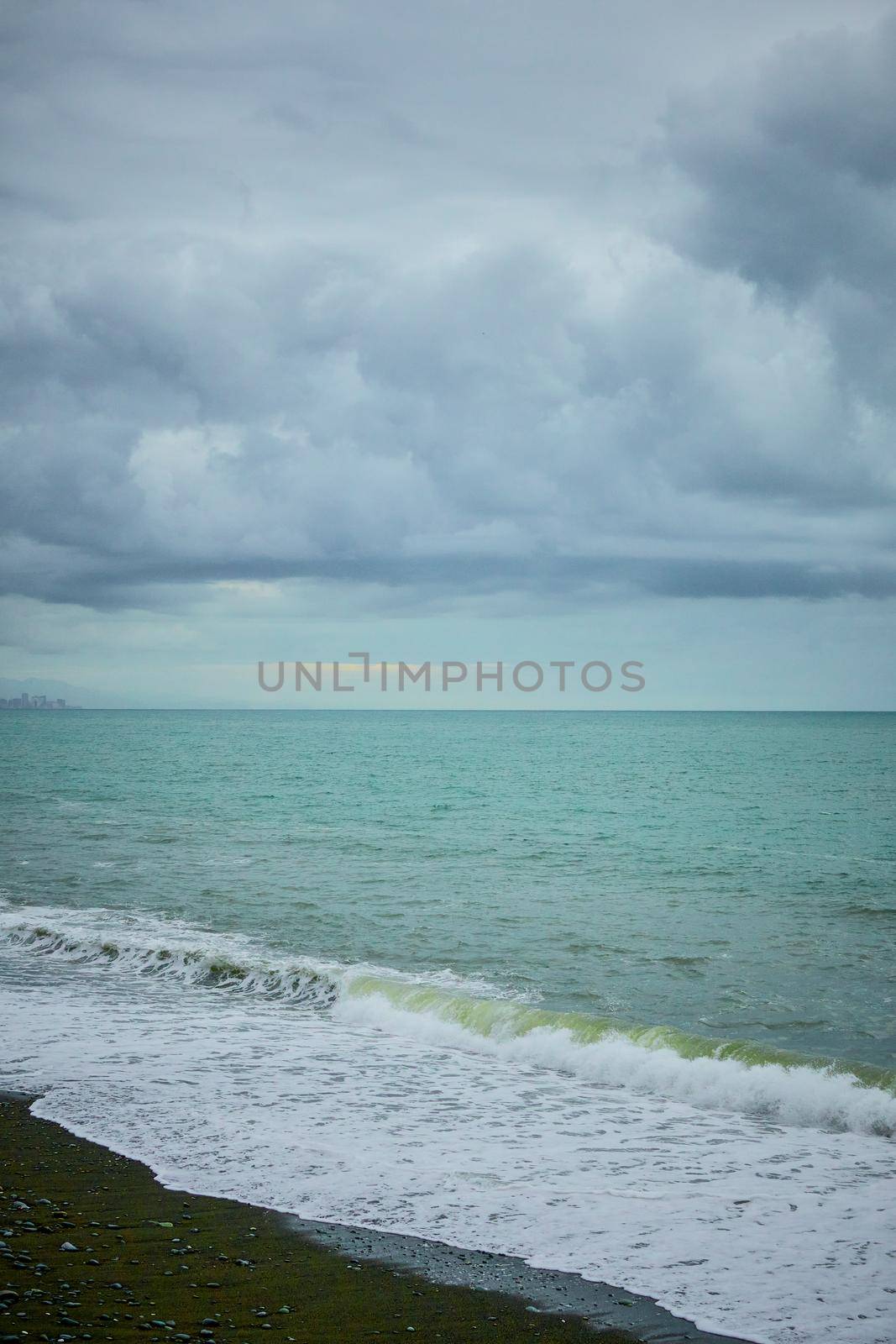 Sea shore with pebbles, wet sea pebbles on the beach and quiet sea surf. Restless sea and waves.