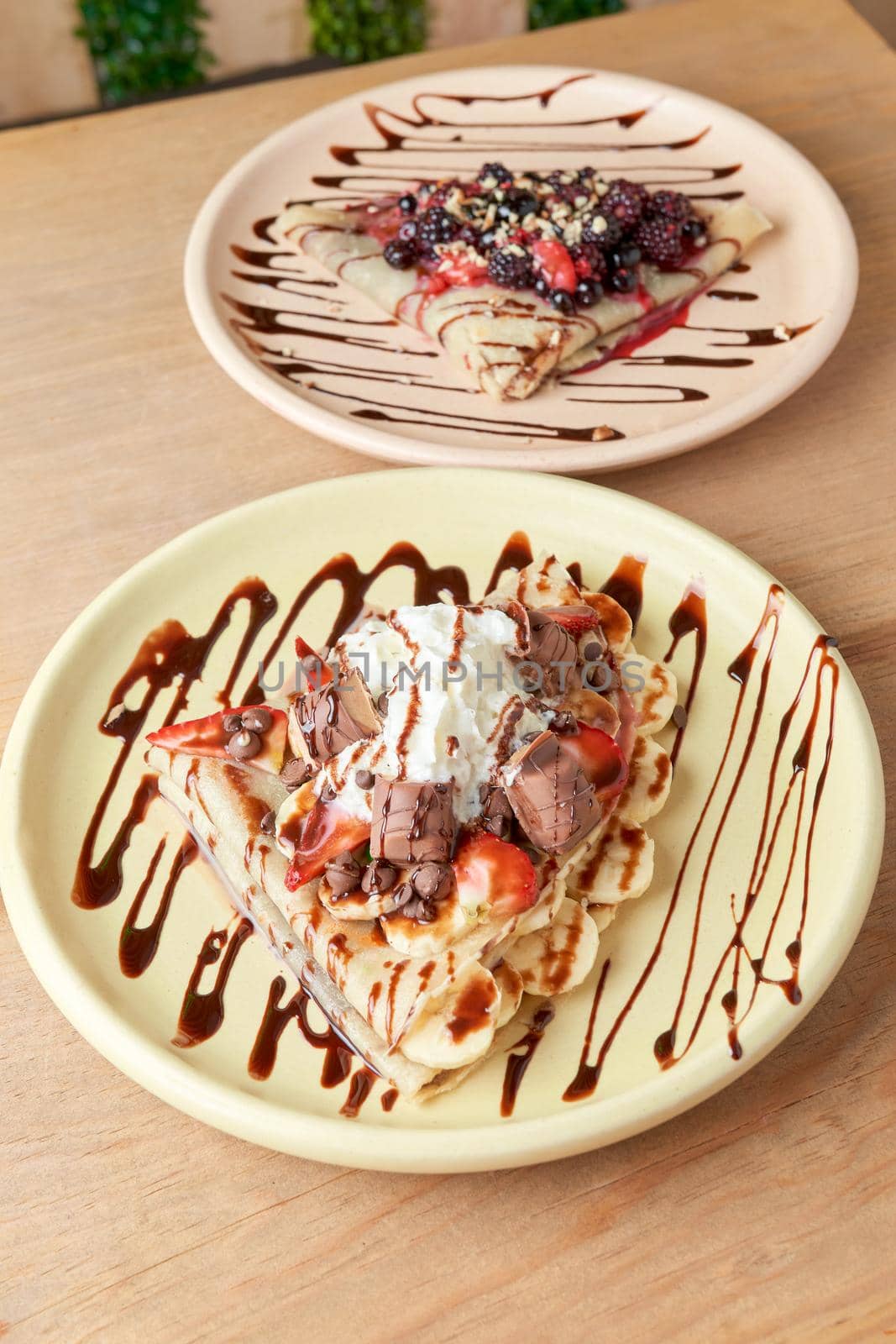 photo of delicious crepe with chocolate, banana, strawberries and whipped cream. sweet crepe.