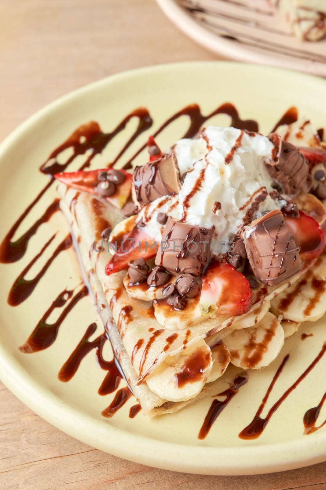 photo of delicious crepe with chocolate, banana, strawberries and whipped cream. sweet crepe.