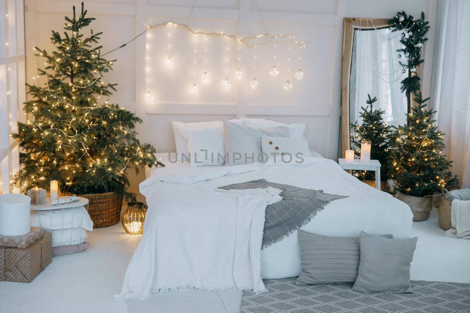 Tver, Russia-November 15, 2019. Embellished mirror, a large bed and a living Christmas tree with lights. New year's interior in bright colors, festive atmosphere, decor, garlands, gifts by Annu1tochka