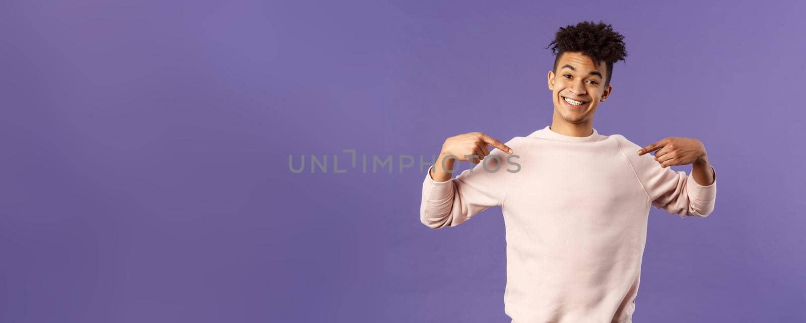 Cute and silly handsome male student pointing at himself and making lovely smile, ready to help offer himself, want participate or being chosen, volunteer to be a candidate, purple background.