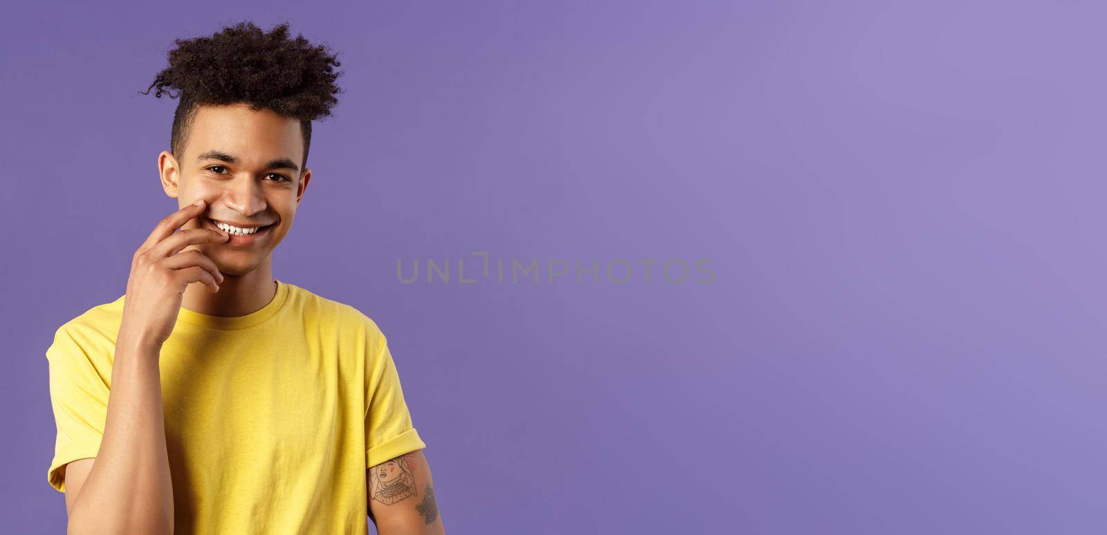 Close-up portrait of lovely young hispanic gay man with dreads, tattoos, touching lip sensually and flirty smiling, checking out someone really cute and handsome, standing purple background by Benzoix