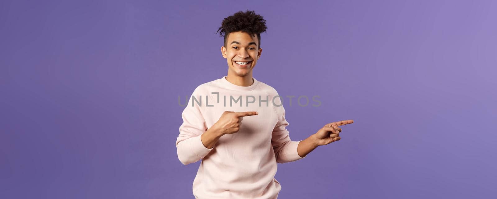 Portrait of young cheerful european guy with dreads, hipster male student inviting join online courses, pay for super cool subscribtion, pointing fingers right, beaming smile at camera, recommend by Benzoix