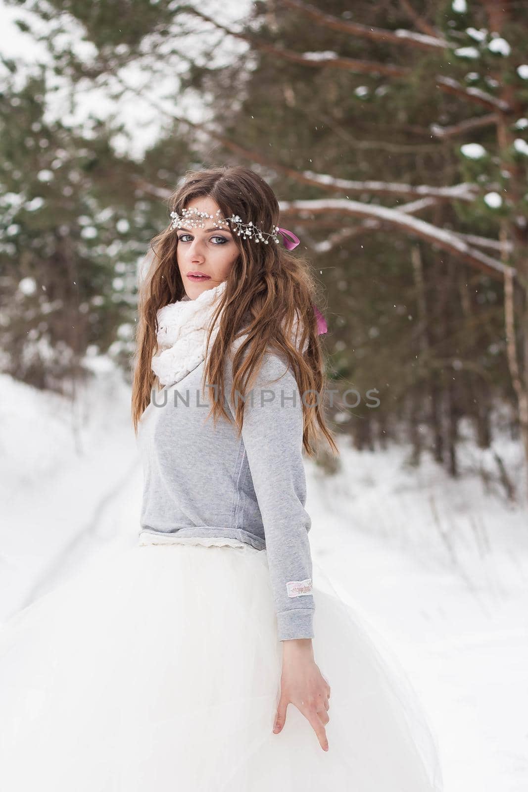 Beautiful bride in a white dress with a bouquet in a snow-covered winter forest. Portrait of the bride in nature.