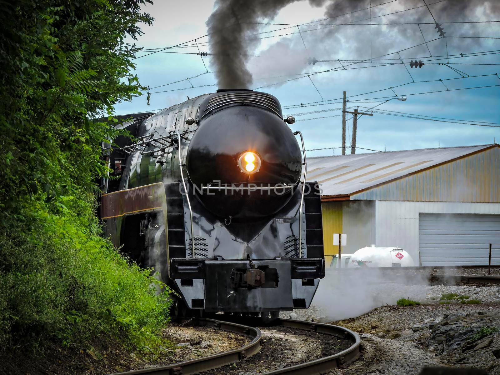 An Antique Restored Steam Engine Approaching Around a Curve Blowing Smoke, on a Sunny Day