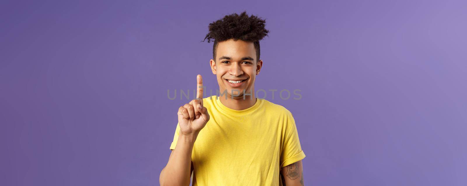 Close-up portrait of funny young teenager, guy picking nose showing index finger and giggle, gagging over his own joke, being nasty and disgusting, standing purple background.