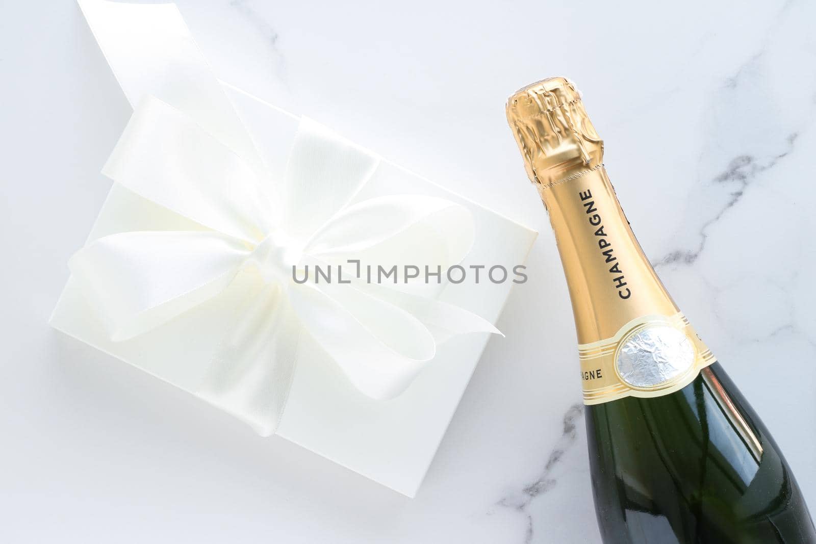 Wedding celebration, lifestyle and luxury present concept - A champagne bottle and a gift box on marble