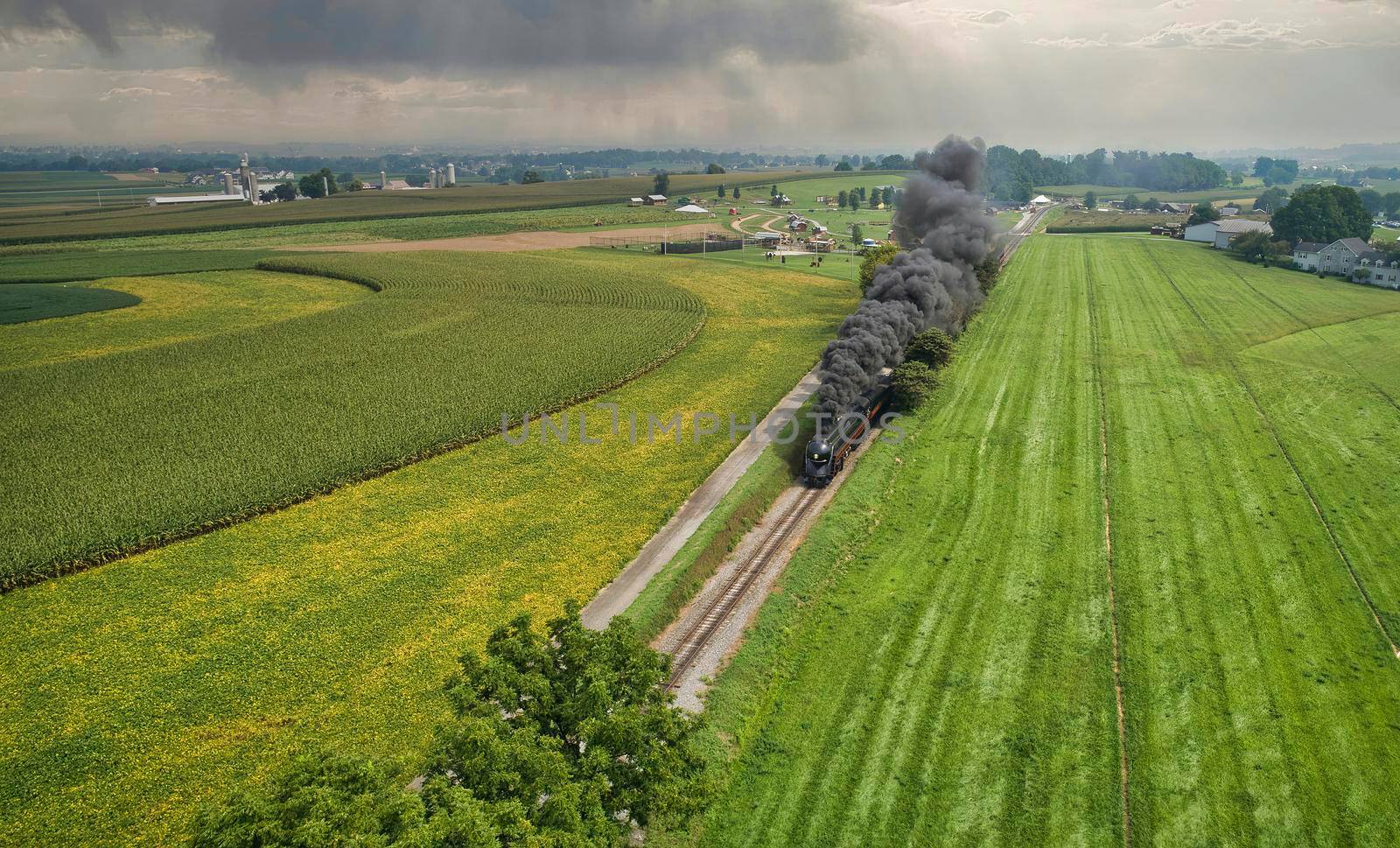 A Drone View of an Antique Steam Engine, Approaching, Blowing Steam and Traveling Along the Countryside on a Sunny Day