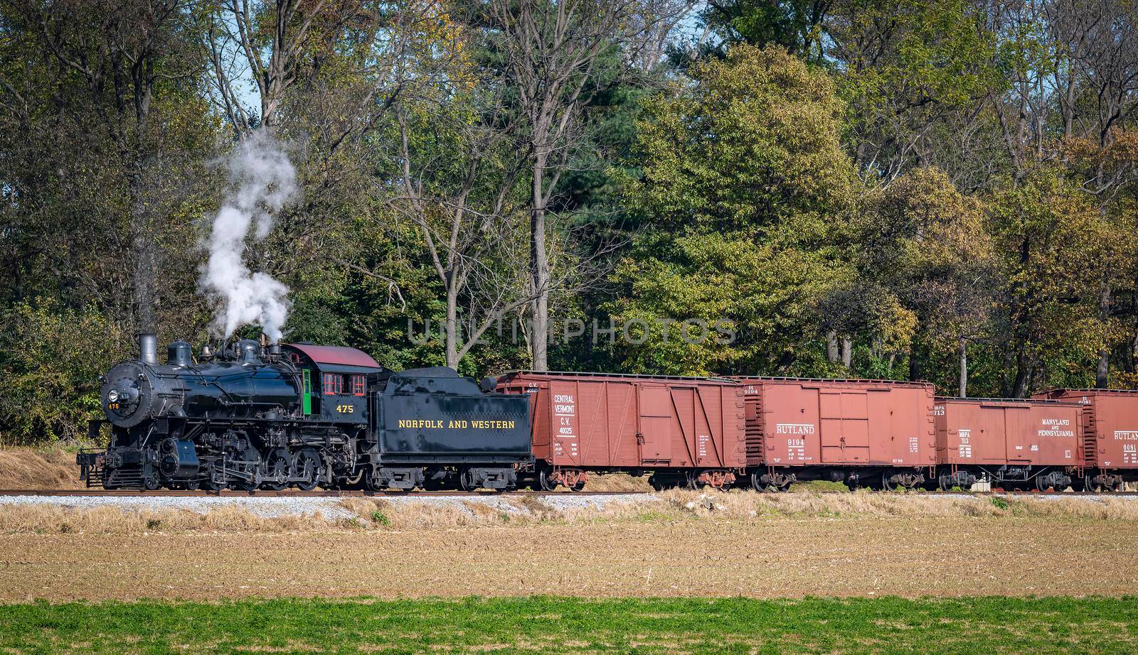 Ronks, Pennsylvania, November 8, 2021 - A View of a Steam Freight Train on a Single Track Going Thru Rural Countryside on a Sunny Day