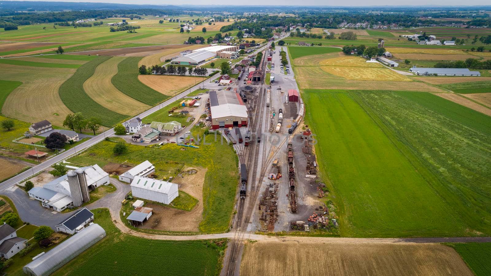 Drone View of a Steam Passenger Station And Freight Yard With Rolling Stock and Empty Tracks on a Cloudy Summer Day