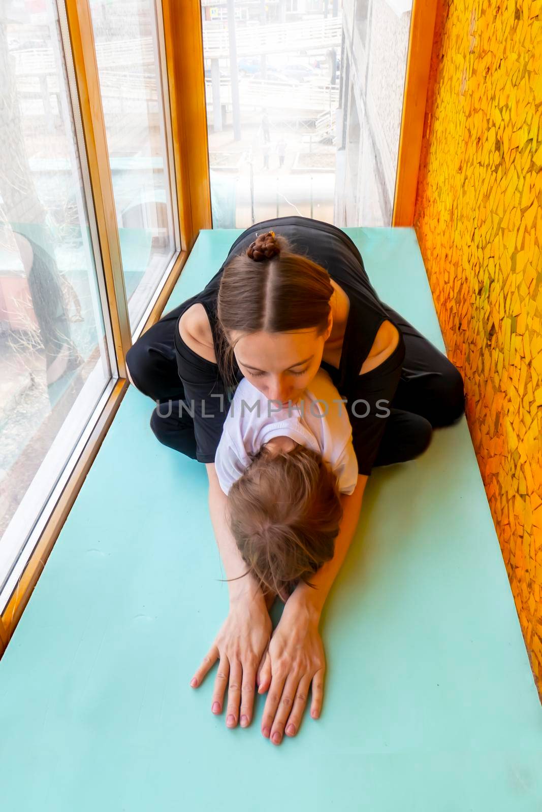 family sport. mother teaches son to do yoga. Helps with stretching. On the balcony In a home apartment.