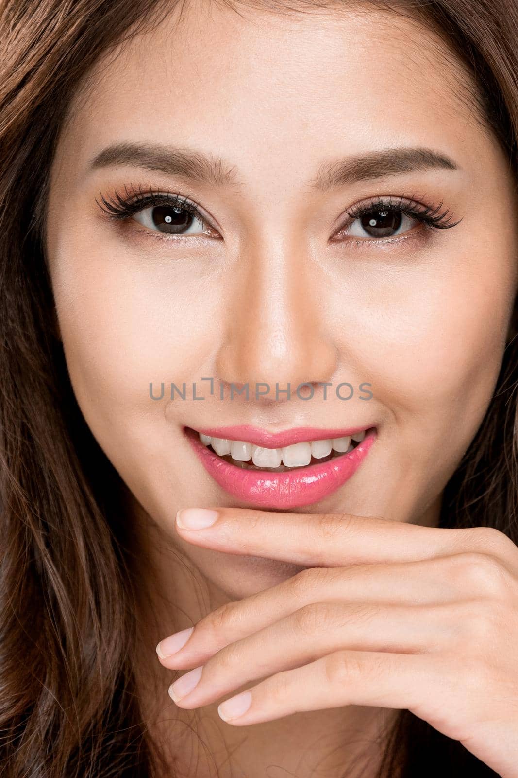 Closeup portrait of ardent young girl with healthy clear skin and soft makeup looking at camera and posing beauty gesture. Cosmetology and beauty concept.