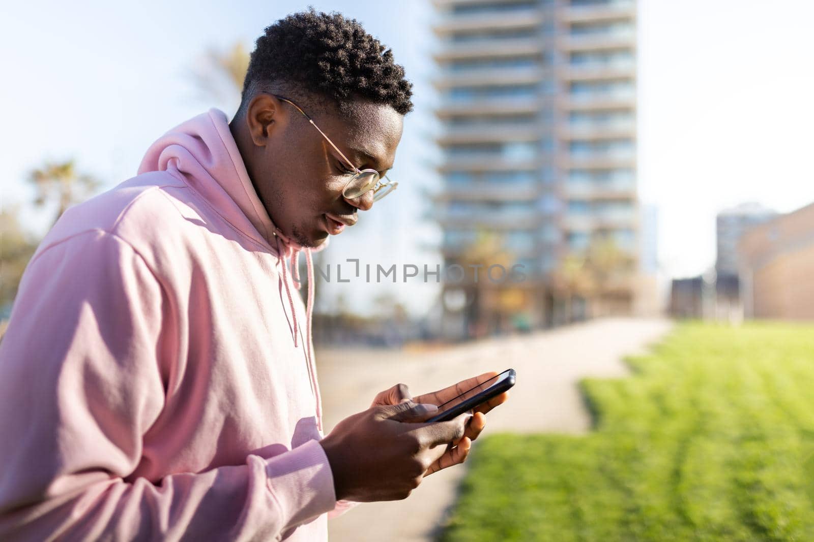 Black man outdoors using mobile phone to send text message. Copy space. Lifestyle concept.