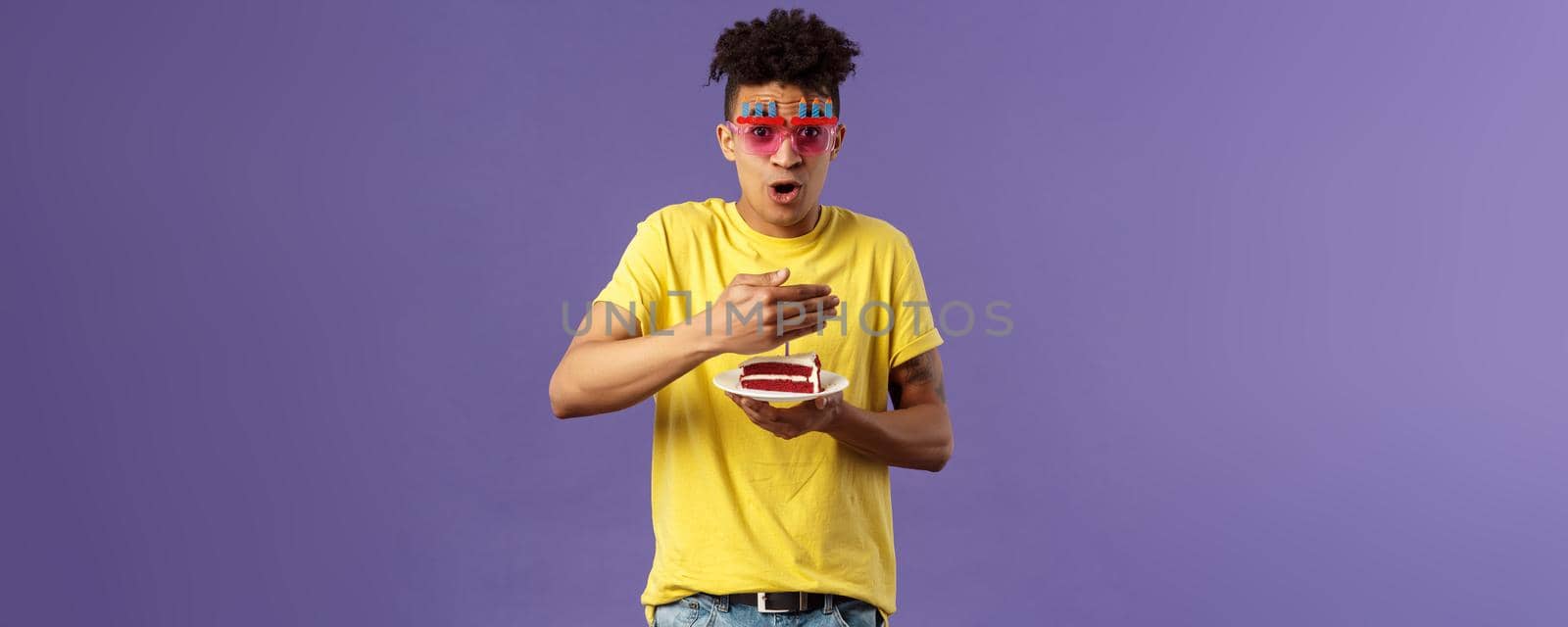 Celebration, party and holidays concept. Portrait of happy funny, enthusiastic young man celebrating birthday, protect lit candle on b-day cake from wind, making wish, smiling cheerful.