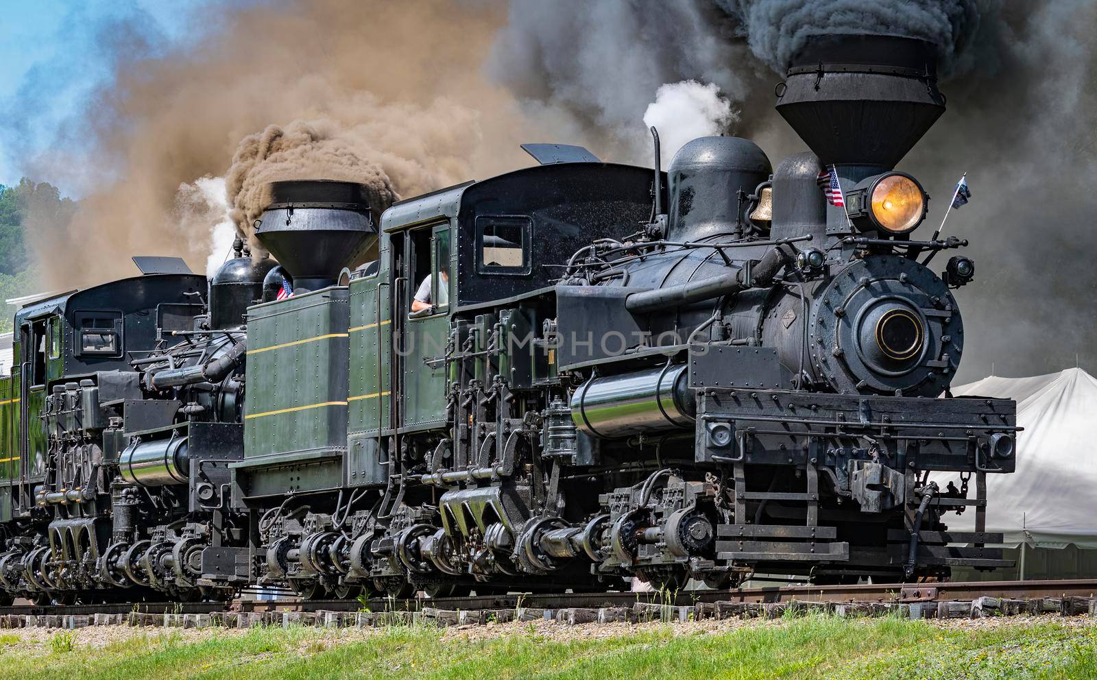 View of Two Shay Steam Engines, Heading Out for a Parade of Steam With the Two Engines Connected Together Blowing Black Smoke and White Steam on a Sunny Summer Day