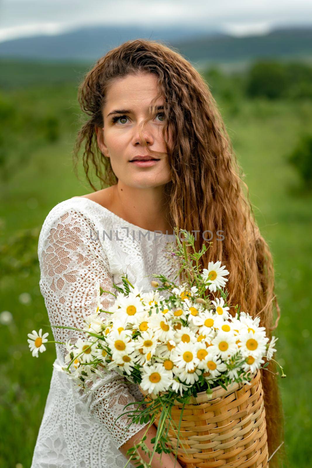 A middle-aged woman holds a large bouquet of daisies in her hands. Wildflowers for congratulations by Matiunina