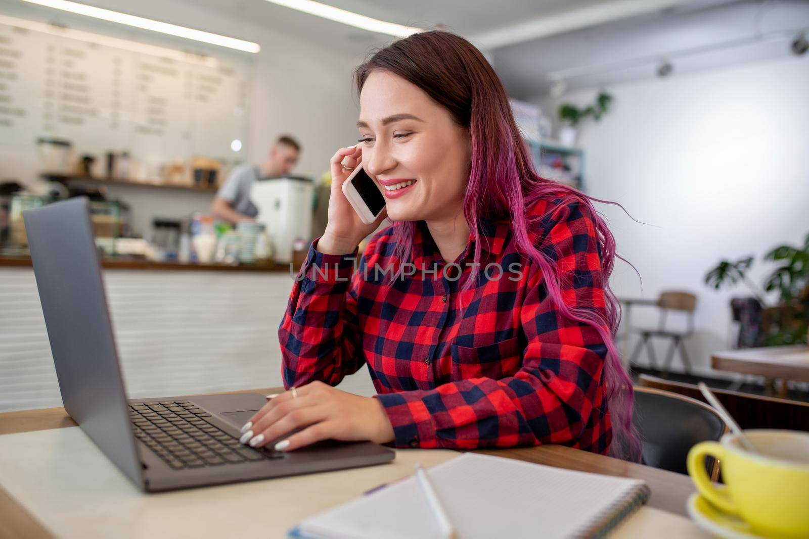 Young woman with pink hair with laptop computer sitting in cafe, intelligent female student working on net-book after her lectures in University