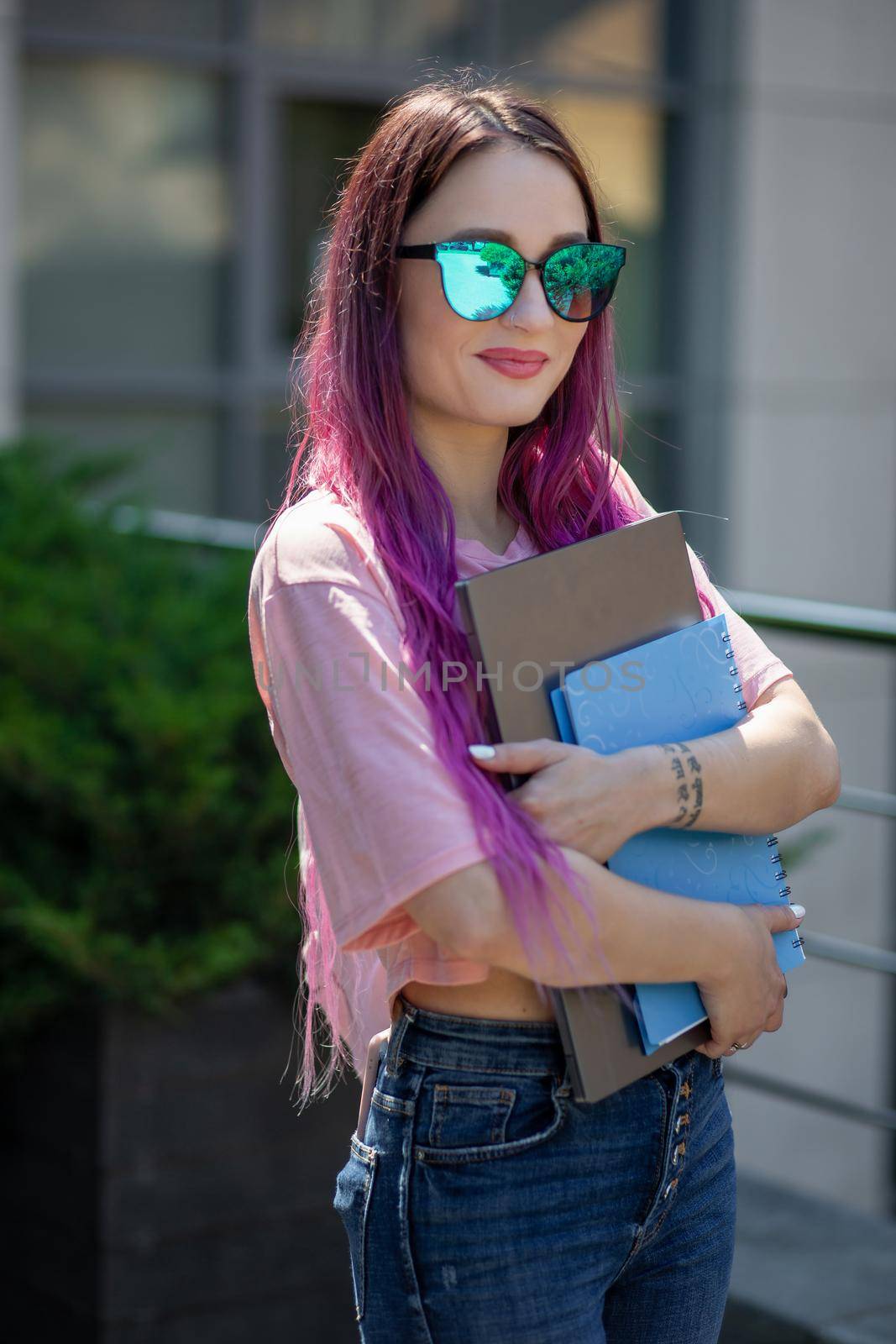 Portrait beautiful female writer dressed in casual outfit holding modern laptop in hand. Young student of faculty journalism having good mood outdoor