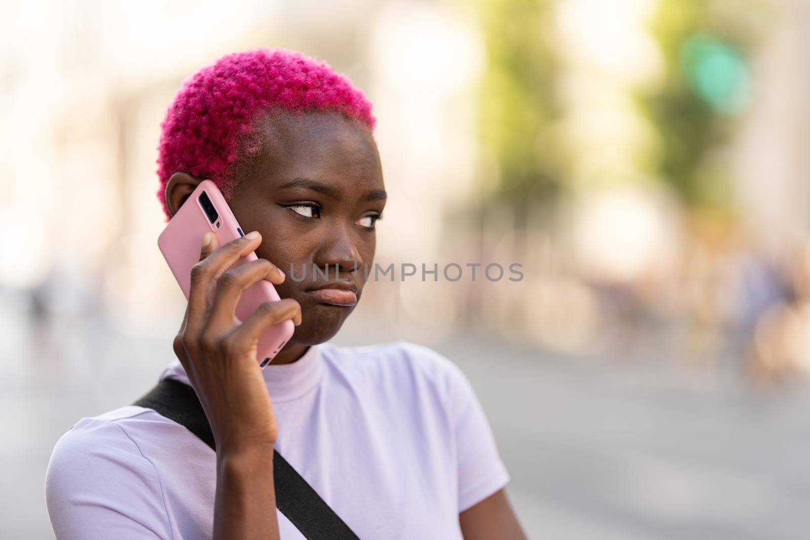 Young african woman with a sad expression talking on the mobile phone in the street