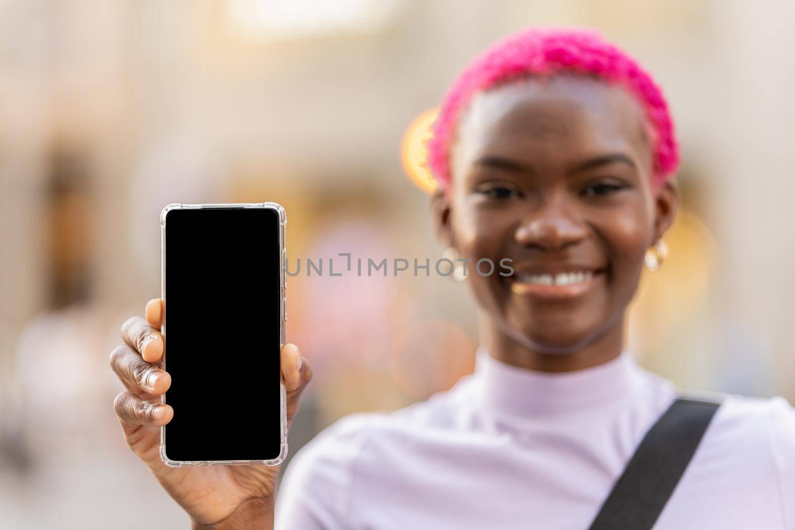 Selective focus on the mobile screen held by a young african woman in the street